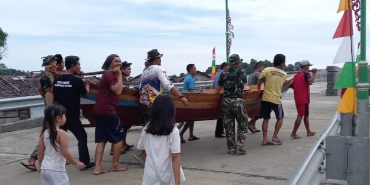 Tingkatkan Solidaritas Bersama Warga DMT, Anggota Satgas 111 Kodim 0315/Bintan Bantu Menggotong Perahu Nelayan.