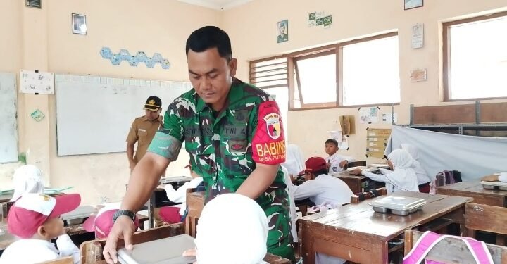 Peran Aktif Babinsa Koramil 0818/13 Kalipare Dukung Program MBG, Serda Istiono Dampingi Pembagian Kepada Siswa SD di Desa Putukrejo